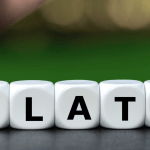 Hand turns dice and changes the word „inflation“ to „stagflation