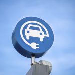 electric vehicle charging sign, blue sky background. Schild zum Laden von Elektrofahrzeugen, blauer Himmel im Hintergrund.