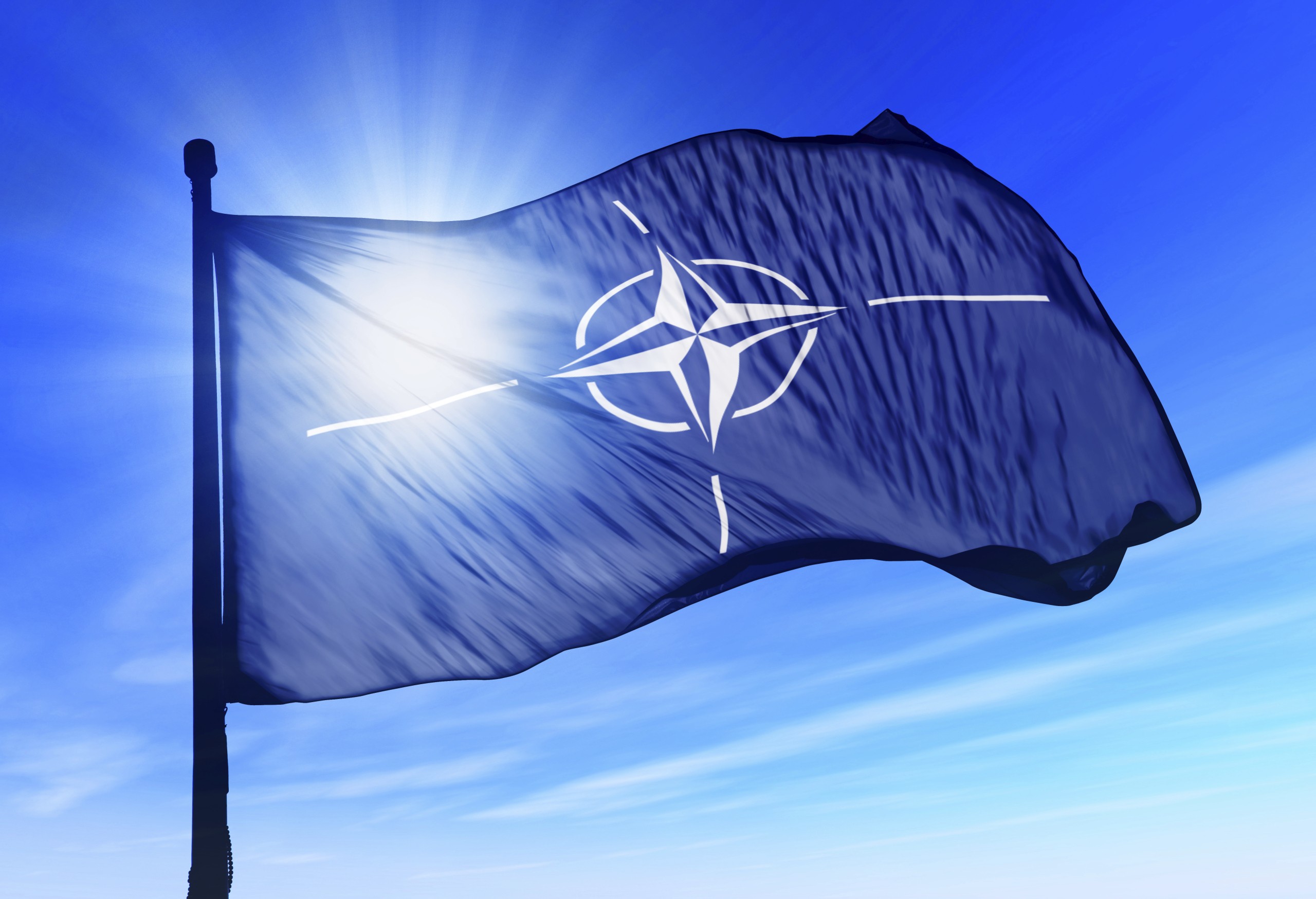 NATO flag waving over the sky, NATO-Fahne flattert am blauen